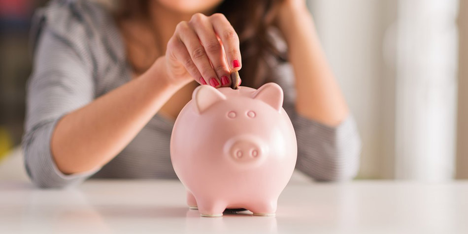 A woman inserts a coin into a piggy bank.
