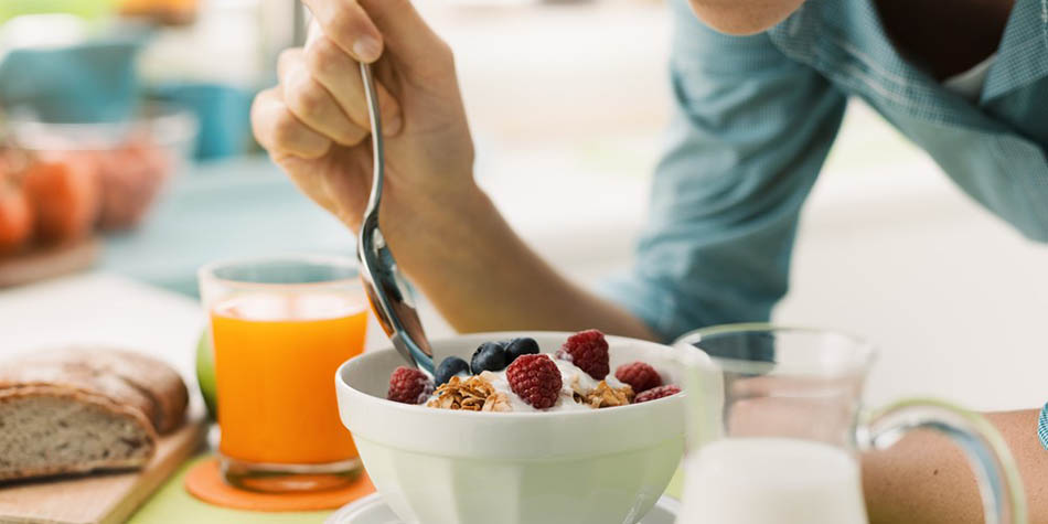 A woman eats a bowl of yogurt topped with berries